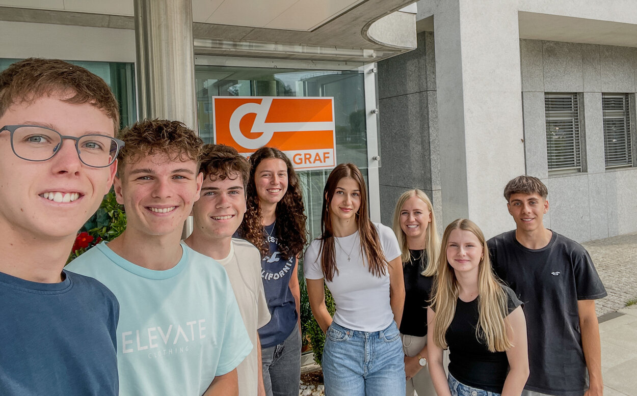 Gruppe von Praktikanten macht Selfie vor Leyrer + Graf Firmengebäude