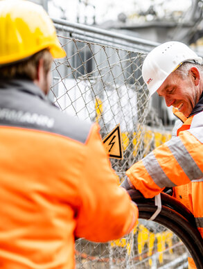 Zwei Ploier + Hörmann Mitarbeiter arbeiten lachend auf einer Baustelle