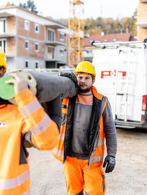 Zwei Ploier + Hörmann Mitarbeiter arbeiten lachend auf einer Baustelle