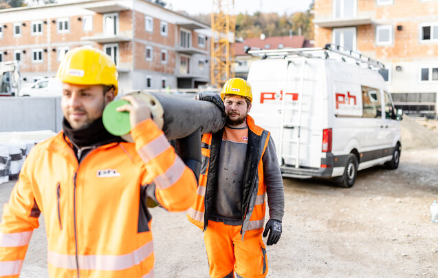 Zwei Ploier + Hörmann Mitarbeiter arbeiten lachend auf einer Baustelle