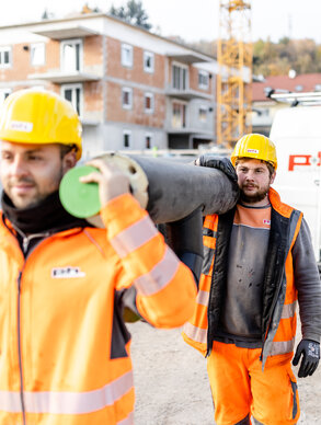 Zwei Ploier + Hörmann Mitarbeiter arbeiten lachend auf einer Baustelle